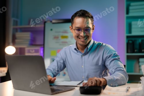 Preview: Commitment Asian businessman sitting at desk in office Working overtime late at night with document
