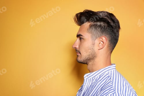 Preview: Young man with trendy hairstyle posing on color background