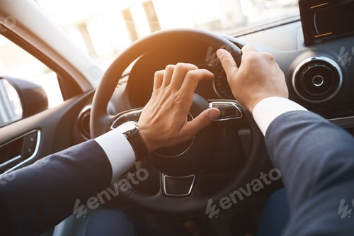 Preview: Close-up of a man driving a car with a hand on a horn button. Sunset filter