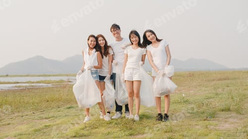 Preview: Portrait group of young multiethnical volunteers help to keep nature clean up looking at camera.