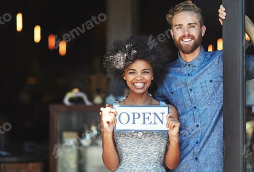 Preview: Portrait of two proud coffee shop owners holding up a sign on opening day