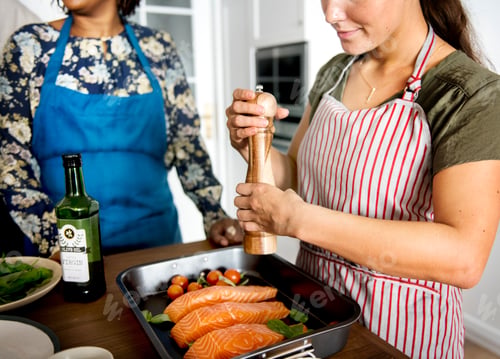 Preview: Woman adding spices and herb to raw salmon