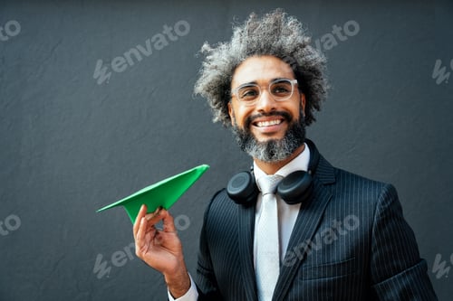 Preview: young entrepreneur throwing a green paper aircraft in the air.