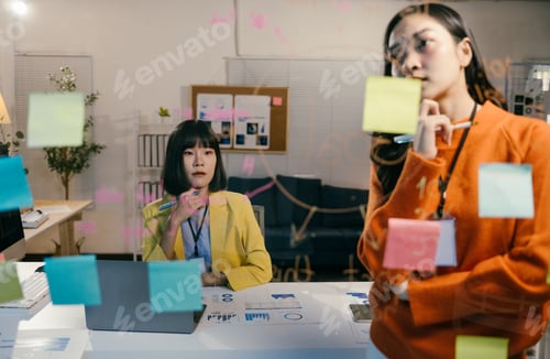 Preview: Two businesswomen are having a brainstorming session in the office. They are writing on sticky notes