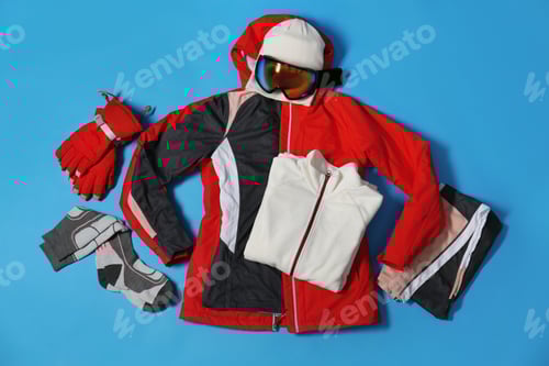 Preview: Stylish winter sport clothes on light blue background, flat lay