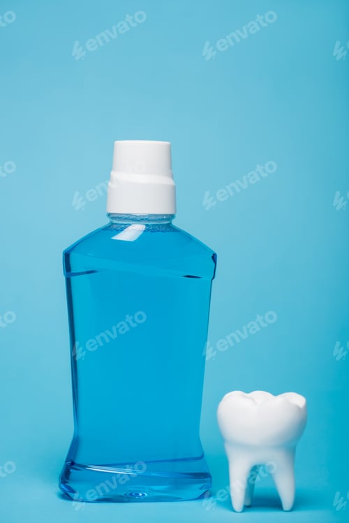 Preview: Tooth model and bottle of mouthwash on blue background