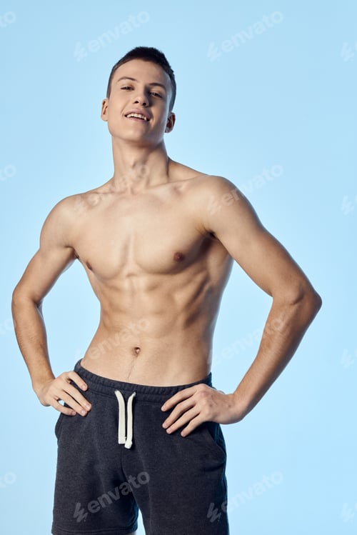 Preview: sporty man with a pumped-up naked torso holds his hands on his belt posing blue background
