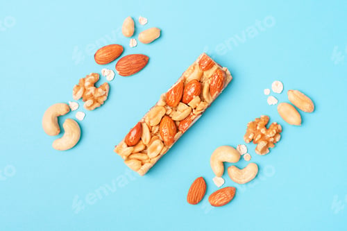 Preview: Protein bar and nuts on blue background close-up top view.