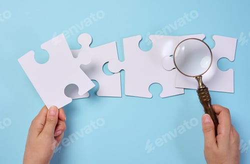 Preview: White empty puzzles and a magnifying glass in hand on a blue background