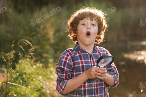 Preview: Cute little boy with magnifying glass in nature