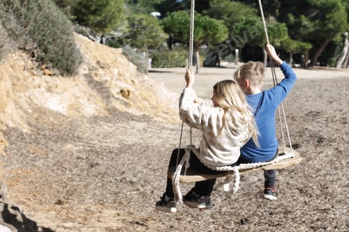 Preview: Kids playing on a swing on the beach