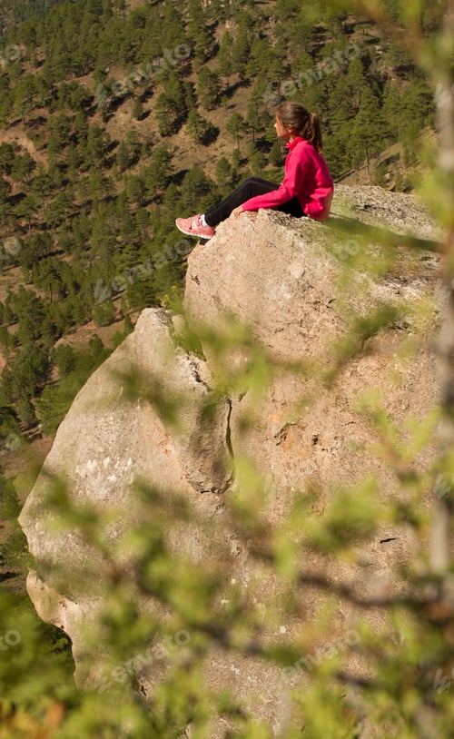 Preview: Young female sitting on cliff