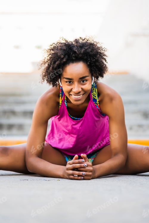 Preview: Afro athlete woman stretching legs before exercise.