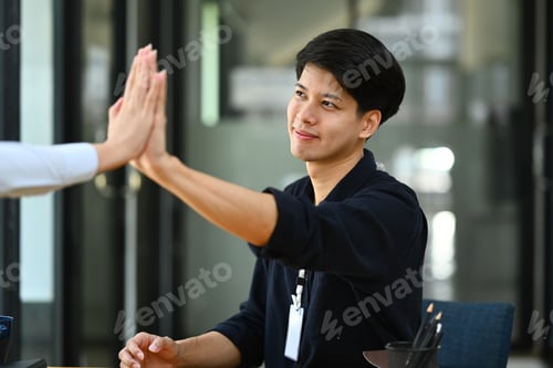 Preview: Celebrating success. Business people giving each other high five.