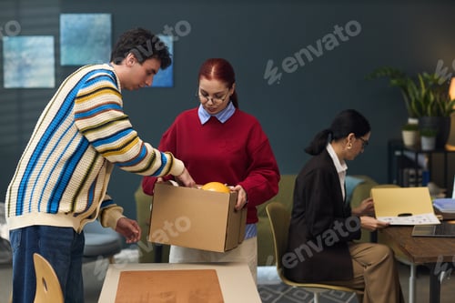Preview: Young Man and Young Woman Packing Items in Cardboard Box