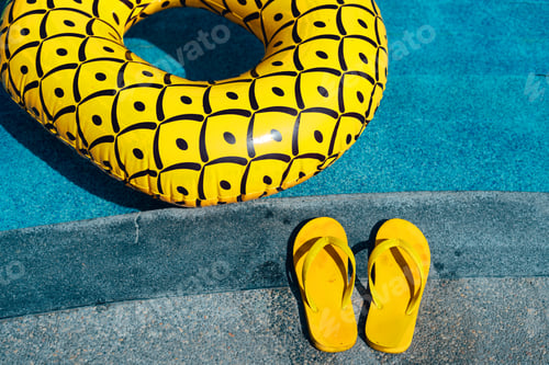 Preview: Yellow sandals and swim rings at the pool on a hot summer day