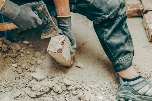 Preview: One young man is cleaning bricks using an axe.