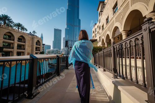 Preview: Enjoying travel in United Arabian Emirates. Young woman in dress walking on Dubai Downtown.