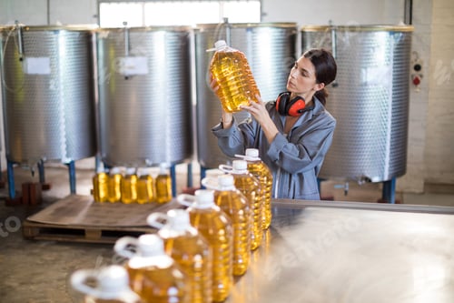 Preview: Female worker checking oil bottles