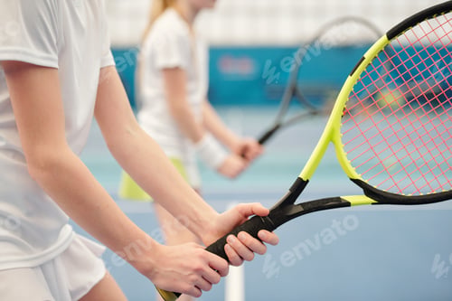 Preview: Hands of active teenage girl standing on stadium and holding tennis racket