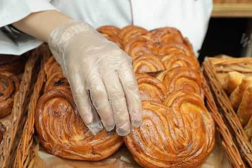 Preview: Baker putting fresh bun onto tray, closeup