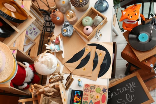 Preview: Sign Garage Sale written on blackboard near many different stuff indoors, above view