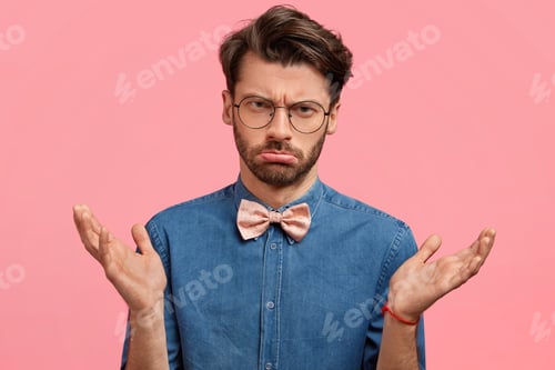 Preview: Disappointed male model has sullen expression, shrugs shoulders in bewilderment, purses lips, has in