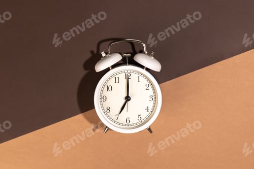 Preview: White alarm clock on a brown background, top view.