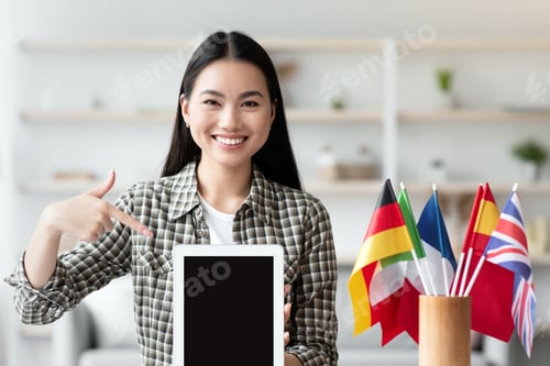 Preview: Happy asian woman pointing at pad with blank screen