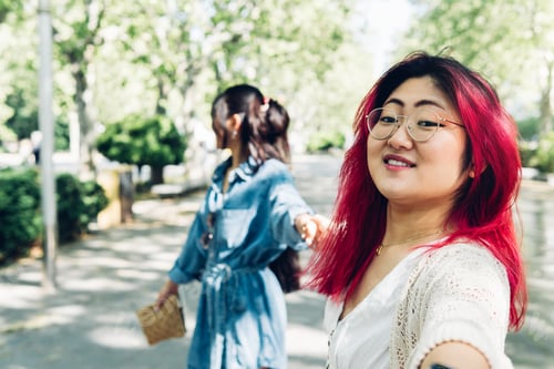 Preview: Asian girlfriends holding hands on a sightseeing trip, concept of bonding and trust.