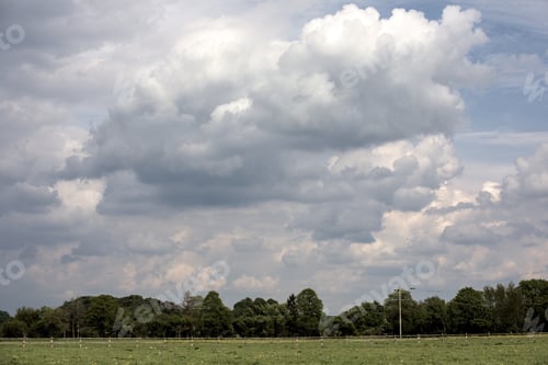 Preview: Horizontal shot of green fenced farmland under the cloudy sky