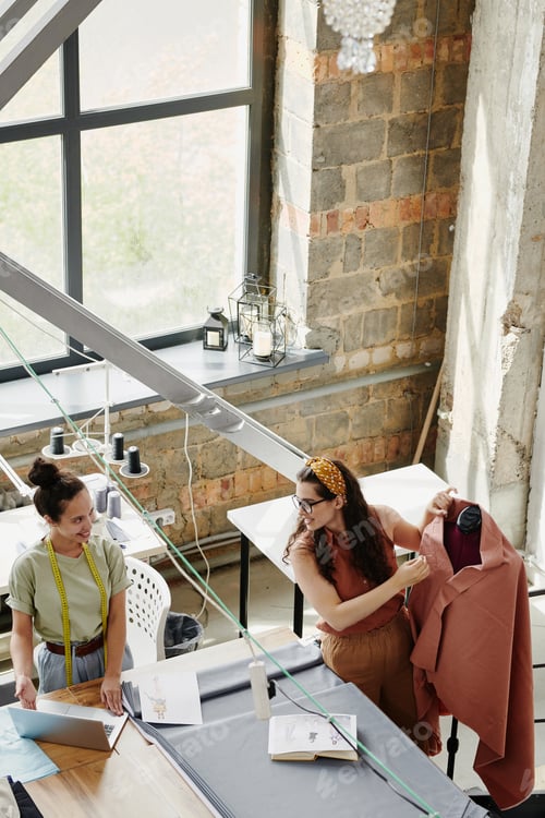 Preview: Happy young creative woman showing her colleague new models on laptop display