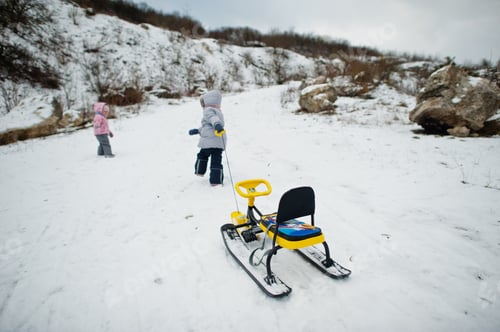 Preview: Two baby girl enjoy a sleigh ride. Child sledding. Kid riding a sledge on winter.