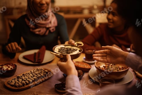 Preview: Close up of Middle Eastern family passing food while eating dinner at dining table.