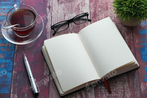 Preview: A cozy workspace featuring an open notebook, glasses, a warm cup of tea, and a lush green plant