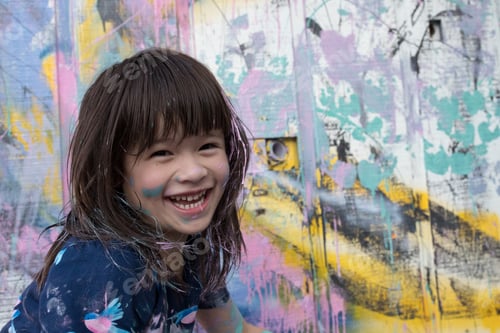 Preview: Portrait of girl by painted wall looking at camera smiling
