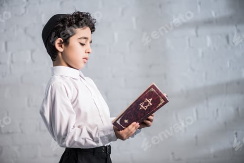 Preview: side view of cute jewish boy in shirt reading tanakh
