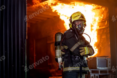 Preview: Firefighter man with protective and safety clothes stand with arm-crossed in front of fire