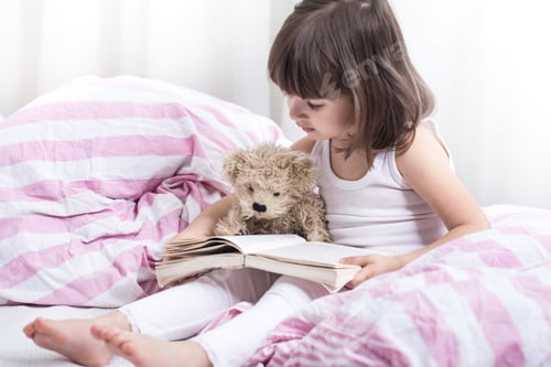 Preview: Cute little girl smiling while lying in a cozy white bed