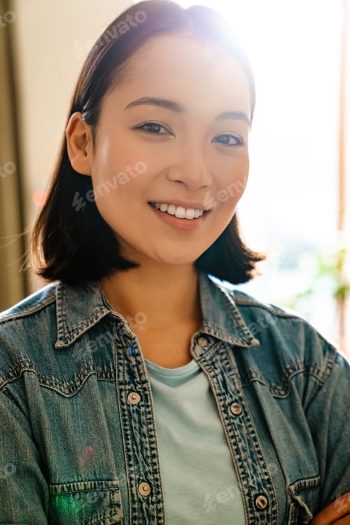 Preview: Young asian woman wearing denim shirt smiling and looking at camera