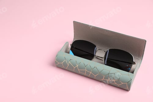 Preview: Case with stylish sunglasses on light pink background, closeup. Space for text