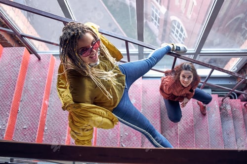 Preview: two young beautiful girls on the stairs top view. modern teenagers. cocky teen millennial