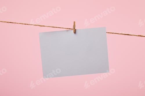 Preview: white empty card hanging on rope isolated on pink
