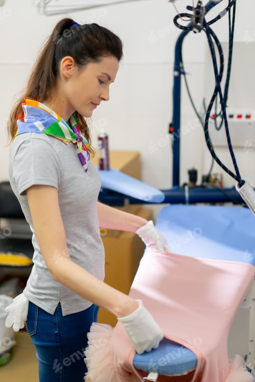 Preview: professional dry cleaning young girl lays out pink jacket for ironing professional equipment