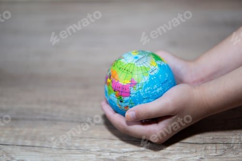 Preview: Side view little girl holding the earth globe in her hands.