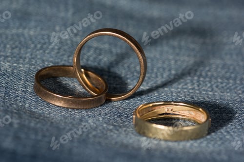 Preview: Still life photography shot of golden rings on a denim surface