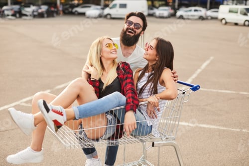 Preview: Joyful ladies sitting in pushcart while having fun with ethnic male friend