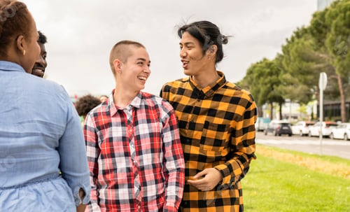 Preview: Two young people of non binary gender enjoy with other friends in a public park.