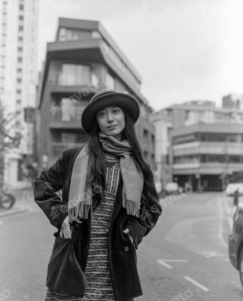 Preview: Stylish woman wearing hat and scarf posing in city street
