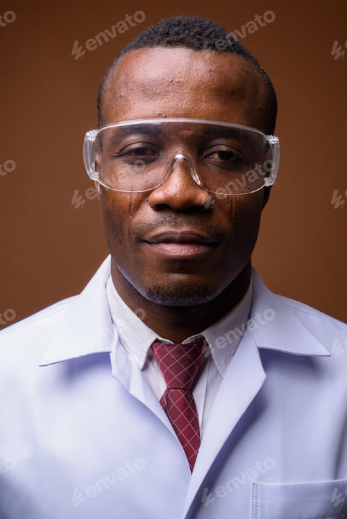 Preview: Studio shot of young African man doctor against brown background